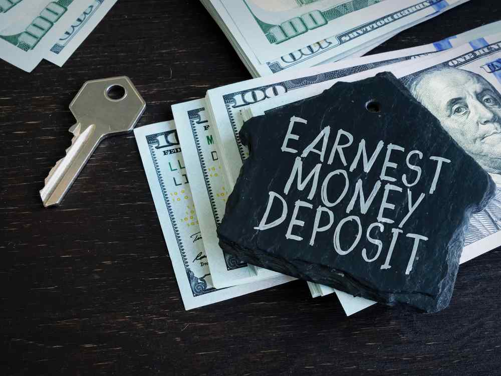 Can A Seller Refuse To Return Earnest Money In Illinois? | Covert Marrero Covert LLP Slate with the words 'Earnest Money Deposit' sits on top of scattered hundred-dollar bills and a key beside it (real estate context).